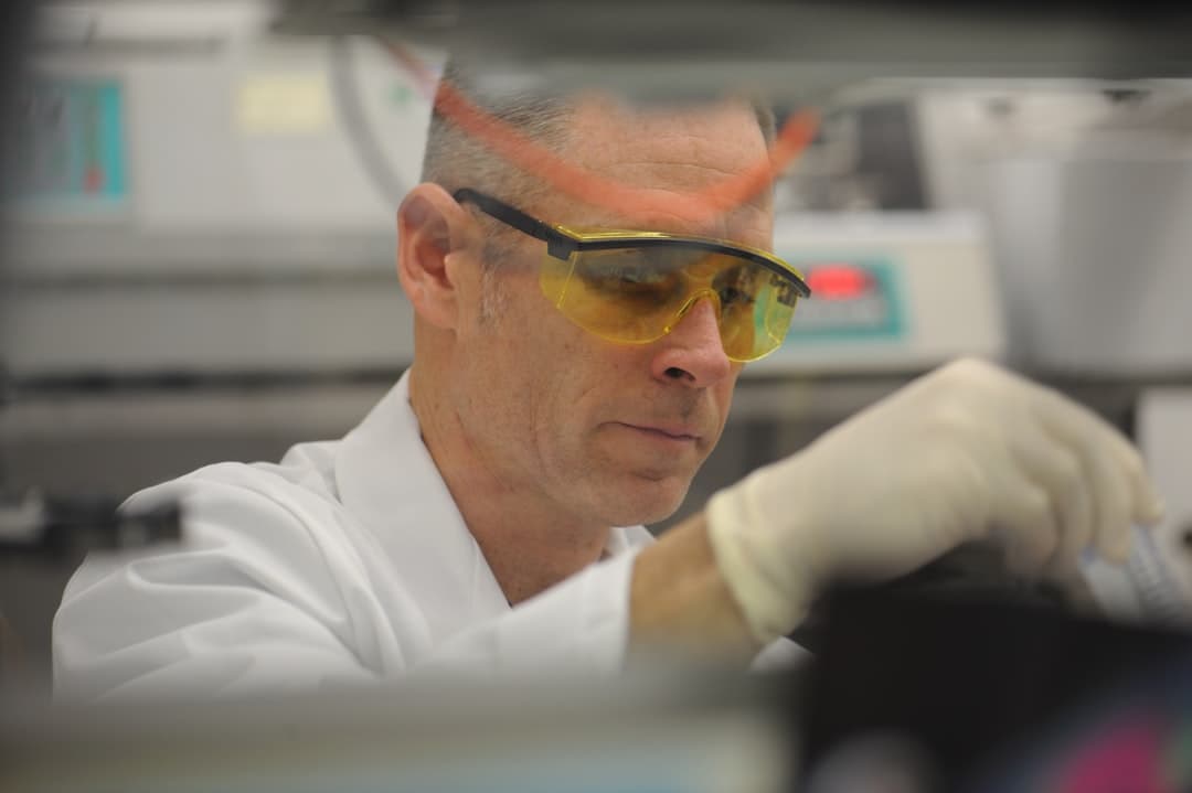 Lab scientist in PPE preparing a water sample for analysis