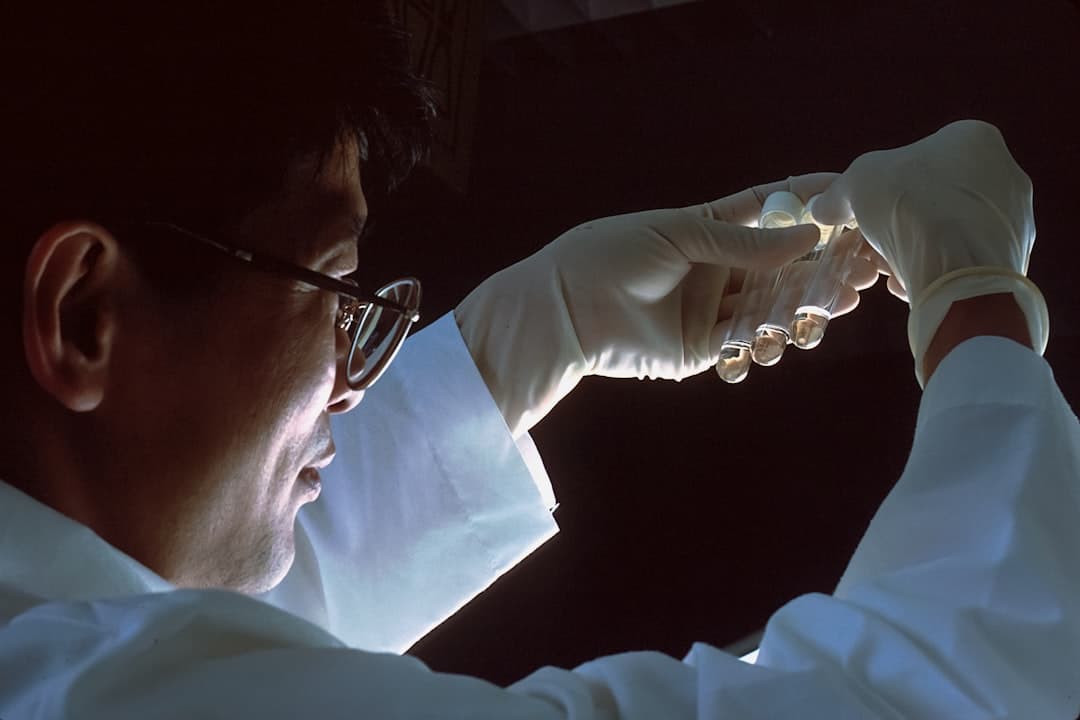Scientist with gloved hands handling a water sample vial