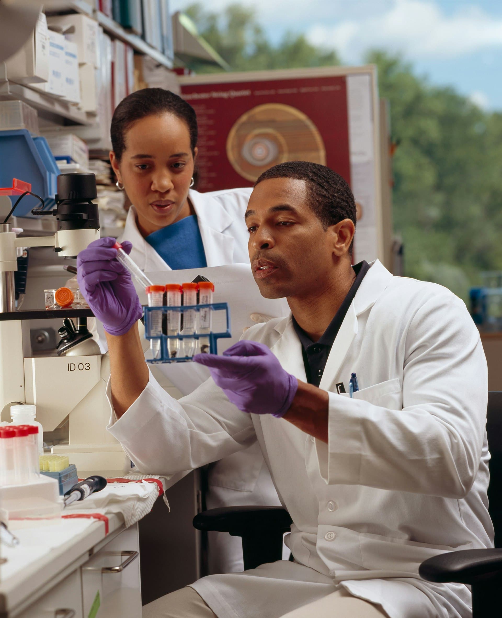 Gloved scientist hands pipetting a sample into a tube